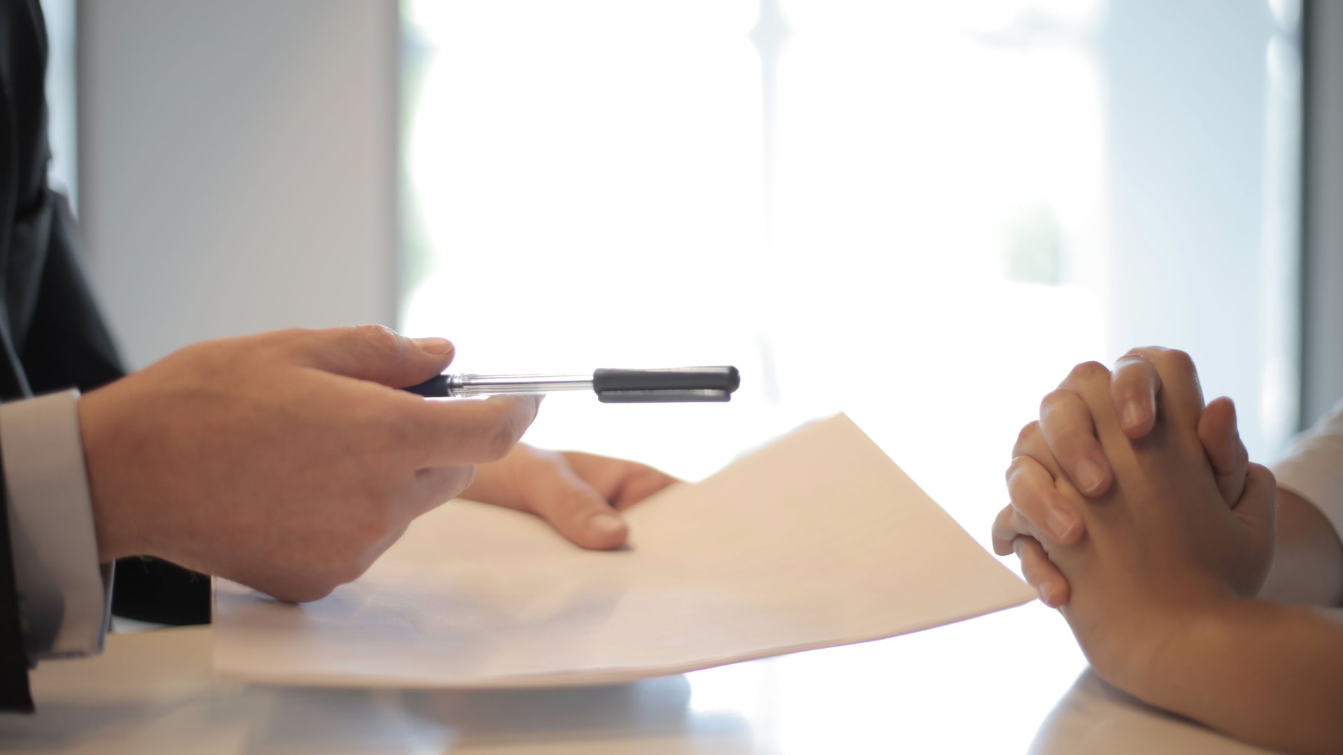 Hands reviewing a paper across a bright consultation table